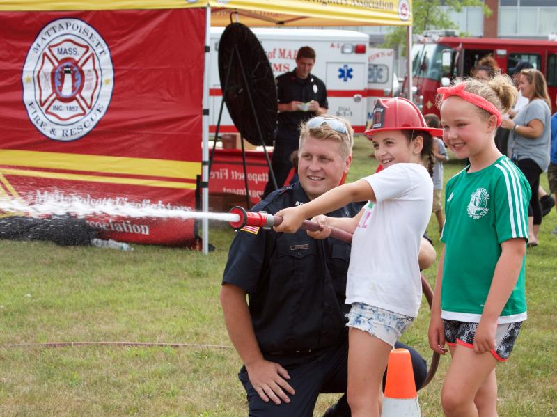 Mattapoisett firefighter Nick Nelson helps Jenna Lynch and Zoe Plante put out a mock fire. BY GEORGIA SPARLING